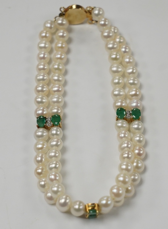 A modern Mexican double strand cultured pearl bracelet, with 14k clasp and emerald and three emerald and diamond cluster set spacers, 17cm. Fair condition.